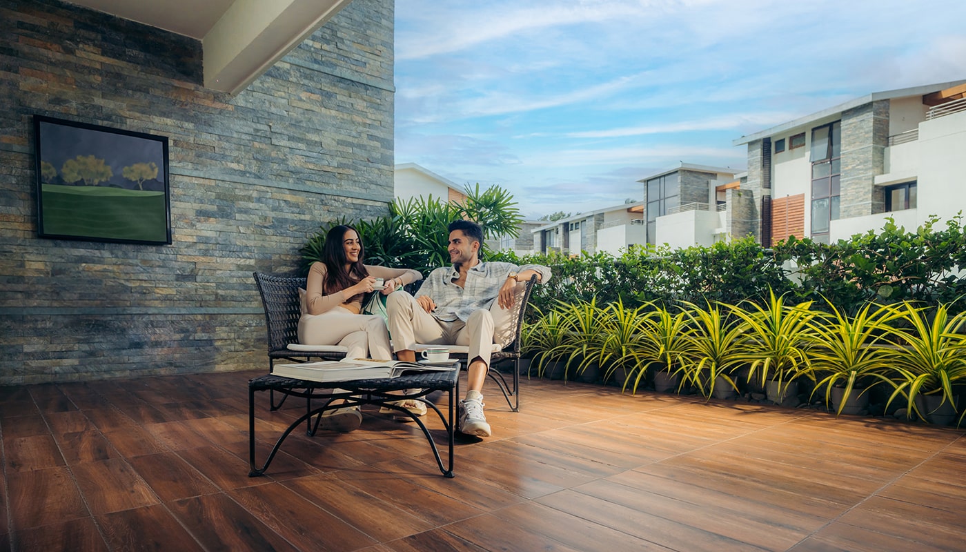 Young couple enjoying coffee and conversation on a spacious private terrace at Embassy Grove, surrounded by lush greenery and premium villament residences in Bangalore
