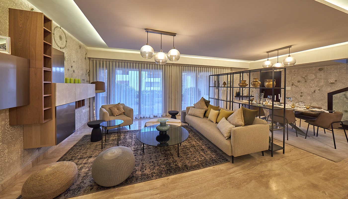 Stylish living and dining area at Embassy Grove featuring modern furniture, designer lighting, elegant décor, and floor-to-ceiling curtains in a premium villament in Bangalore