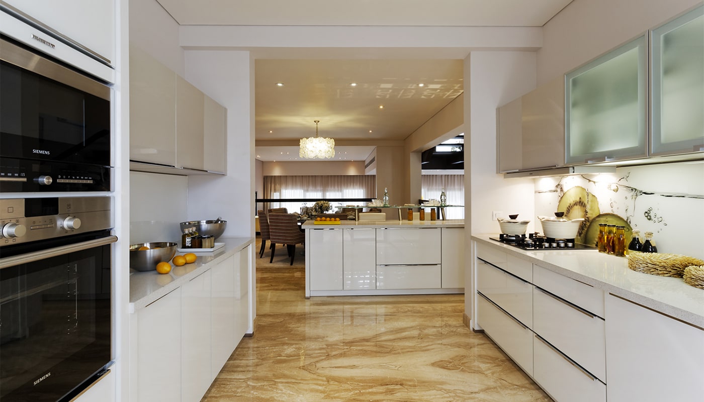 State-of-the-art modular kitchen at Embassy Grove featuring high-end Siemens appliances, sleek white cabinetry, ambient lighting, and elegant open access to the dining area in Bangalore