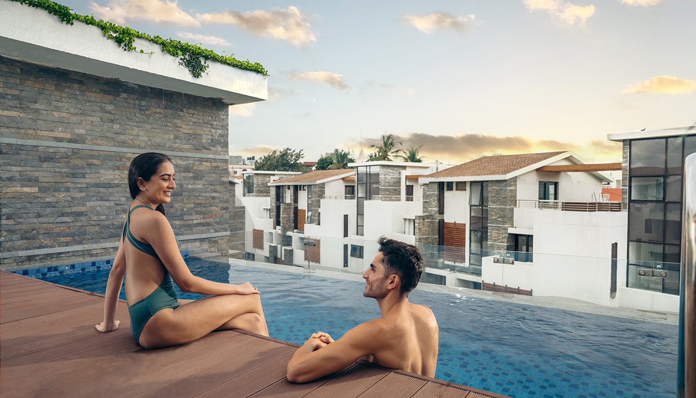 Smiling couple enjoying a sunset moment by the private rooftop pool at Embassy Grove, surrounded by modern villament residences in Bangalore.