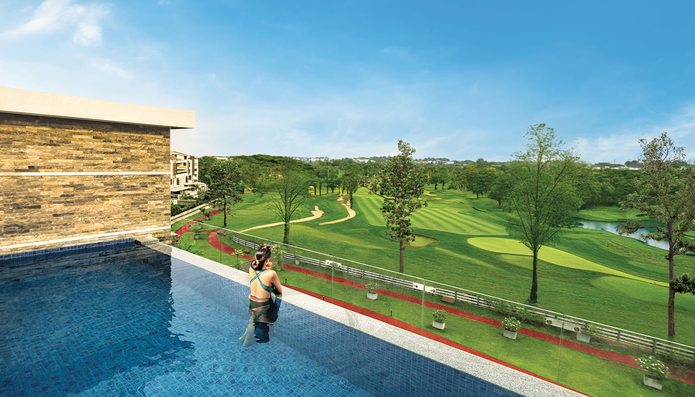 Woman enjoying a panoramic view of the lush golf course from a private rooftop infinity pool at Embassy Grove, overlooking the Karnataka Golf Course, Indiranagar.